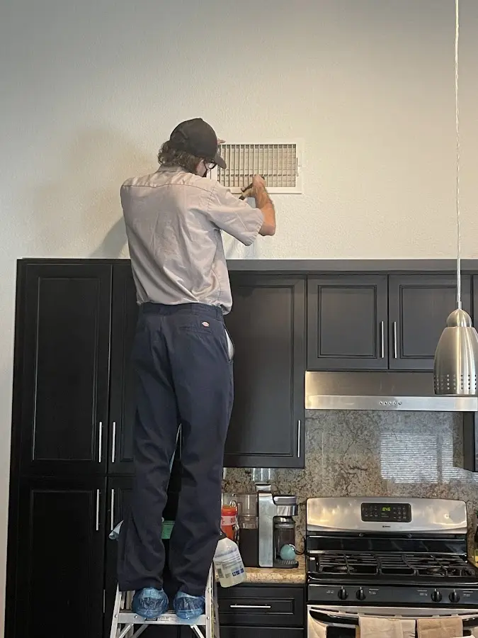 Technician inspecting an air vent during HVAC service in Paris
